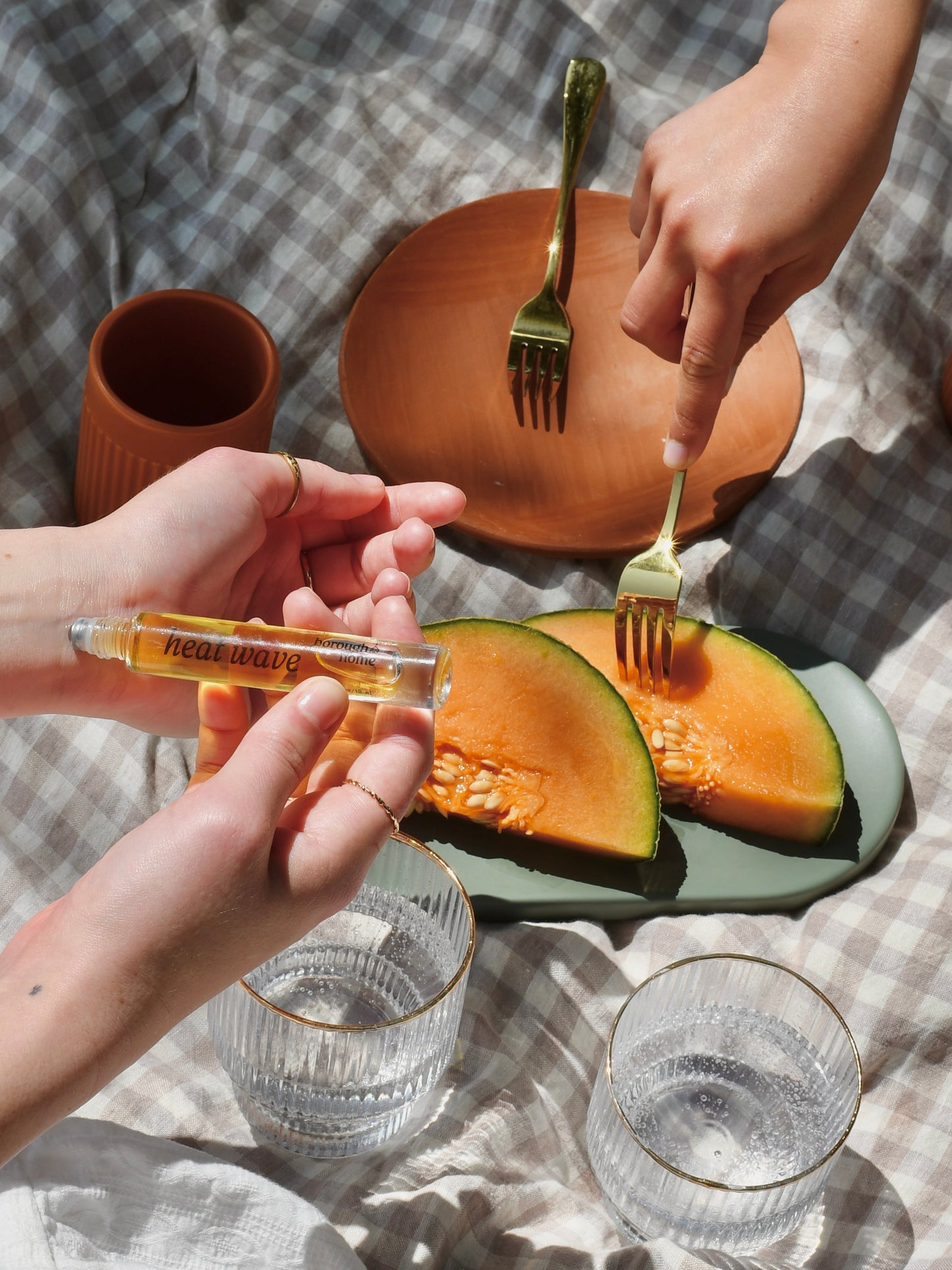 Heat Wave Perfume Oil Rollerball being applied by model to wrists during a picnic