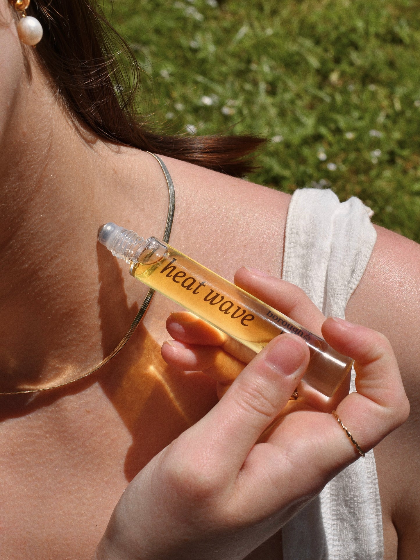 Heat Wave Perfume Oil Rollerball, applied by model to neck.