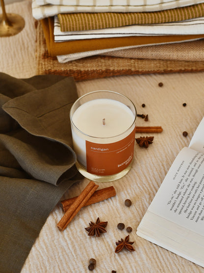 Cardigan candle next to blankets, top down view.